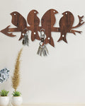 Wooden wall hook with bird designs holding keys against a light background
