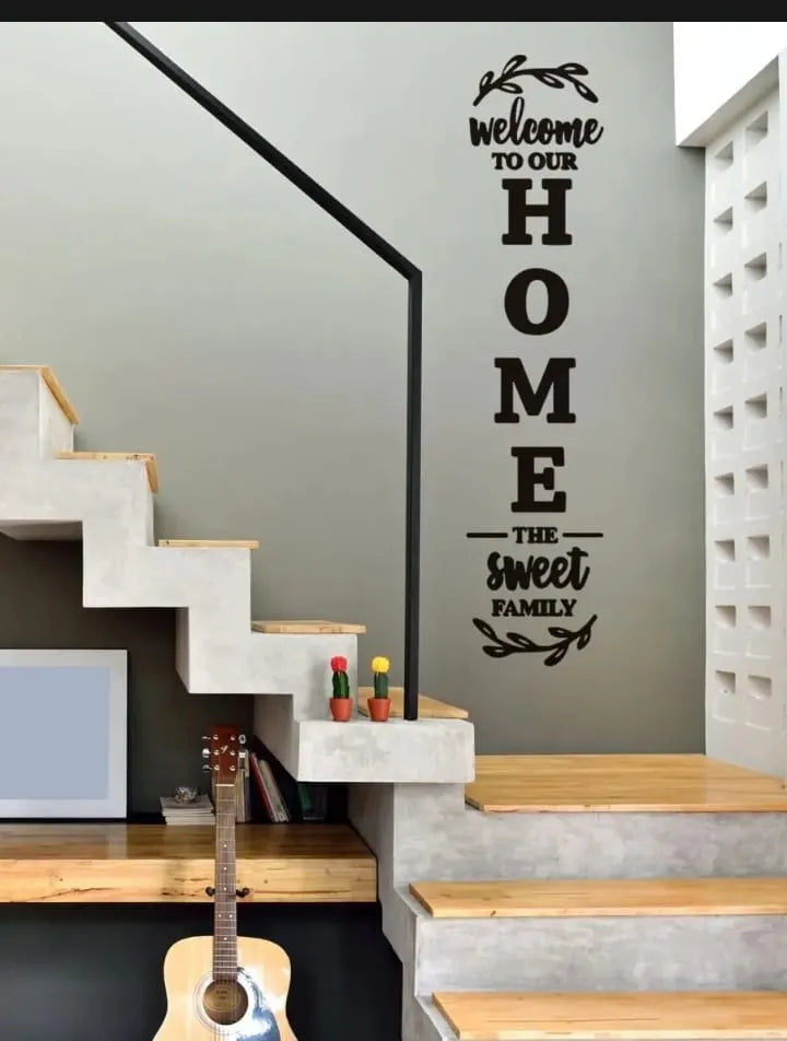 Wall decal with 'Welcome to our home, the sweet family' text on a staircase wall.