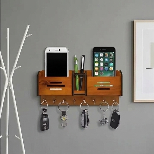 Wooden wall organizer with phone stands, key hooks, and a pen holder on a gray wall.
