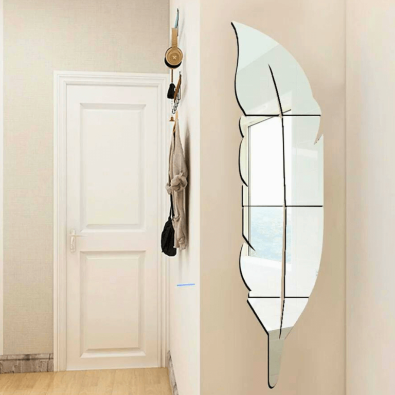 Decorative wall mirror shaped like a feather in a room with a door and light-colored walls.