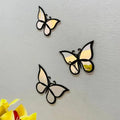 Three butterfly-shaped mirrors on a light gray background with yellow flowers at the bottom.