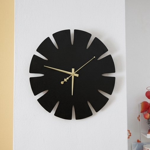 Black wall clock with a unique design on a white wall.