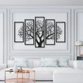 Five framed black and white tree artworks on a wall above a white sofa.